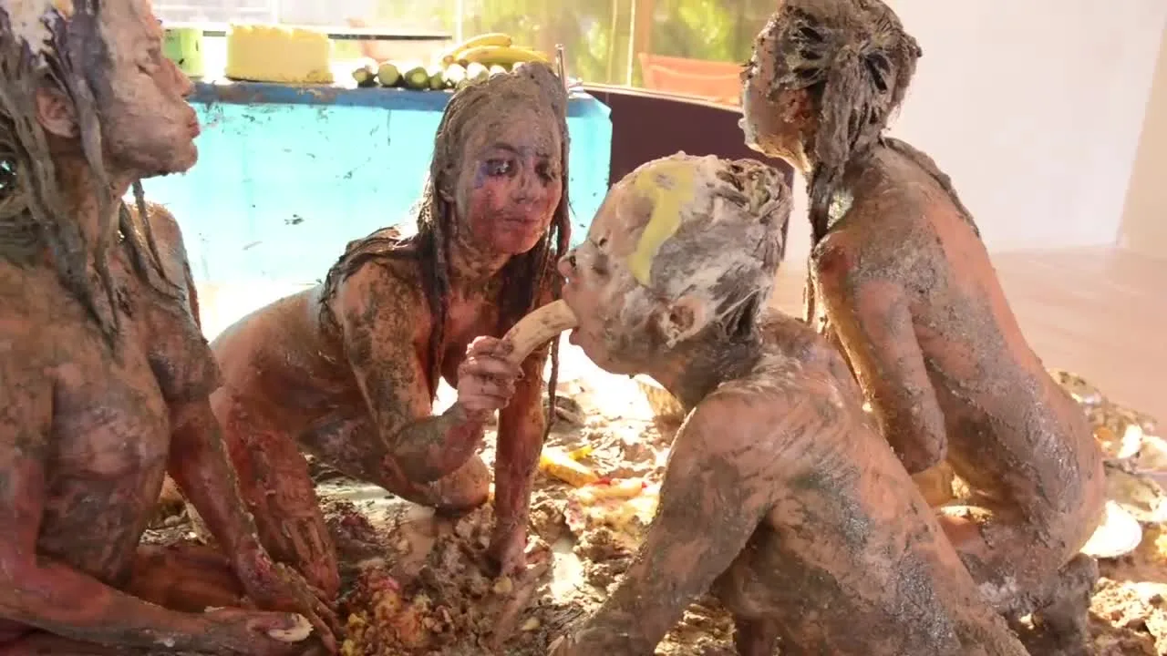 Three slim girls covered in mud, one bends over getting licked out