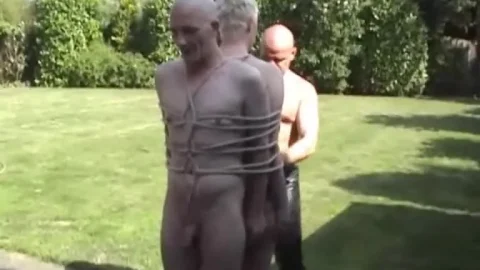 Two bald white guys in backyard B&D with ropes and cat-o’-nine-tails