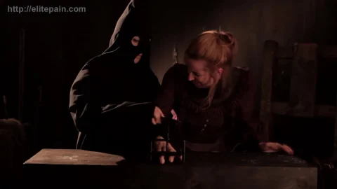 Redhead in chains cuts herself while blonde helps in dungeon scene
